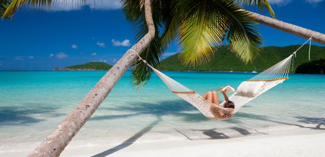 woman reading a book in hammock at the Caribbean beach